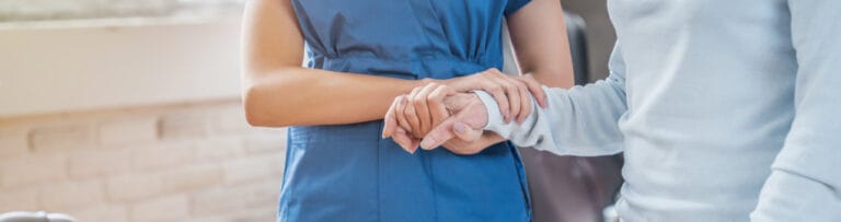 Close-up of caregiver and resident holding hands