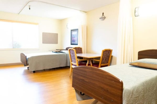 Bright resident room with two beds and a table