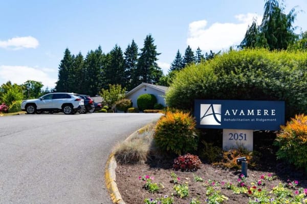 Facility entrance showing landscaping and vehicles