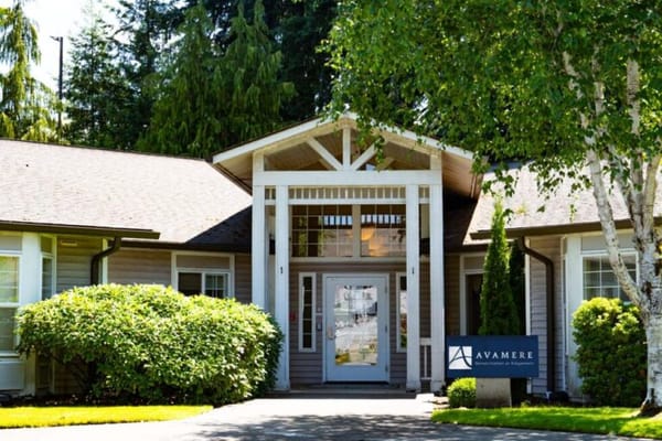Entrance of a senior living facility surrounded by greenery