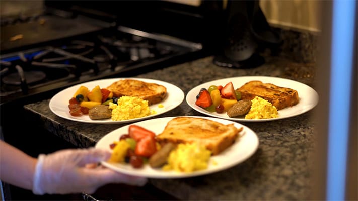 Plates of colorful breakfast food being served