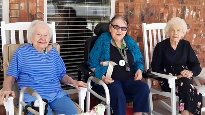 Three residents enjoying a sunny day on the porch