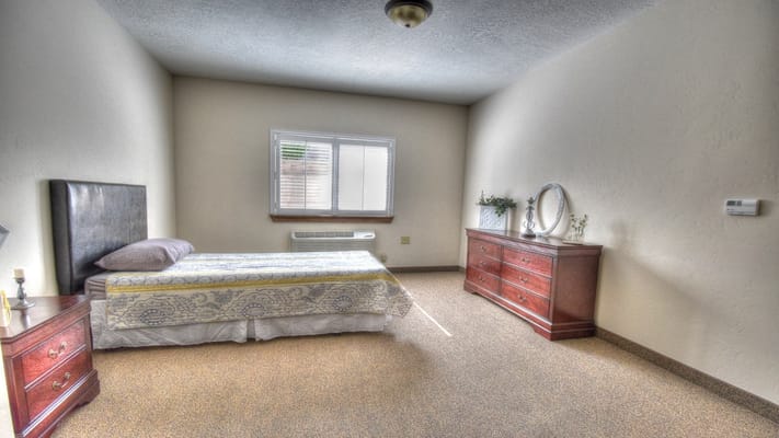 A cozy private bedroom with a bed and dresser