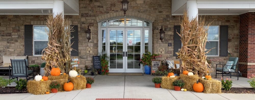 Front entrance decorated for fall with pumpkins and hay bales