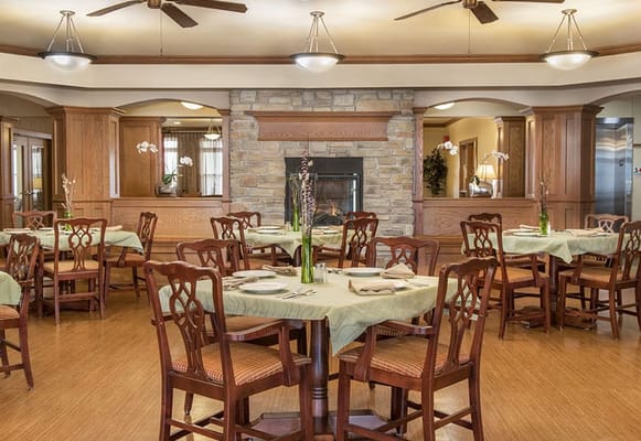 Dining room with tables set for meals and a fireplace