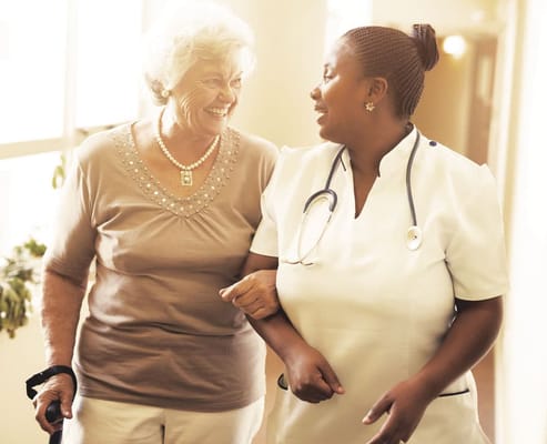 A nurse assisting and smiling with a senior resident