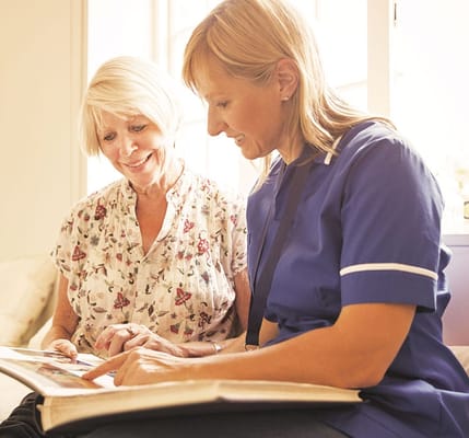 A caregiver and resident looking at a photo album together