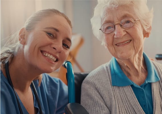 Caregiver and resident smiling together in an interior setting