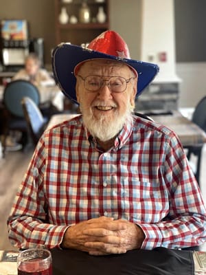 Resident wearing a festive hat in a dining area