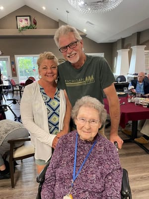 Resident posing with two visitors in a common area