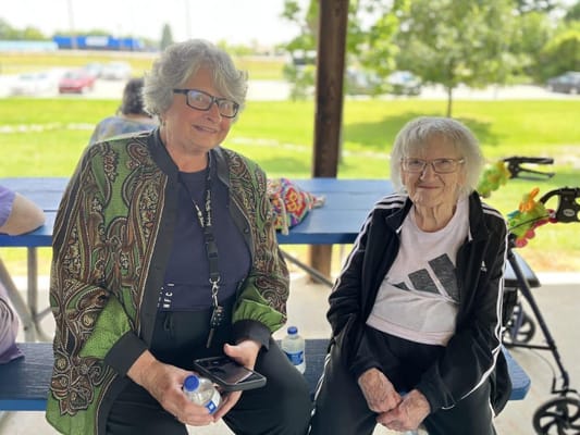 Two women sitting at a picnic table outdoors