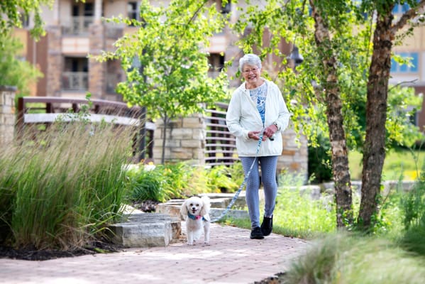 Elderly resident walking a dog on a pathway