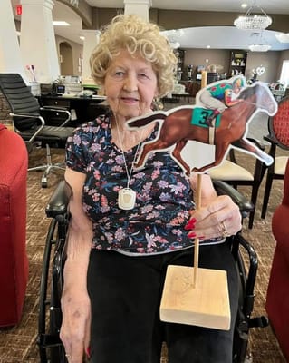 Resident holding a horse racing cutout in an activity room