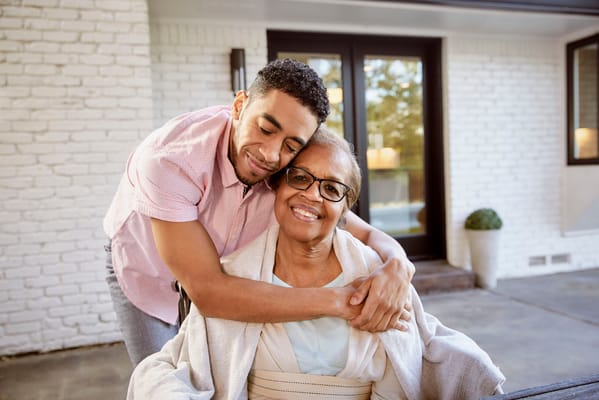 A caregiver embracing a resident outside a facility