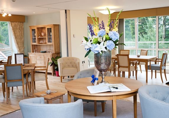 A bright common area with wooden furniture and flowers