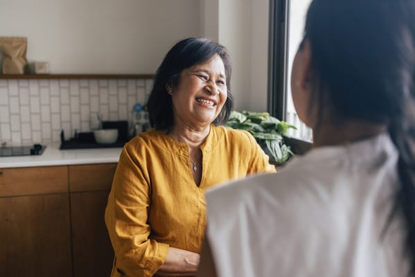 A smiling older woman engaged in conversation indoors