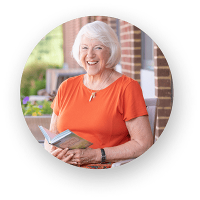 A smiling resident reading a book outside