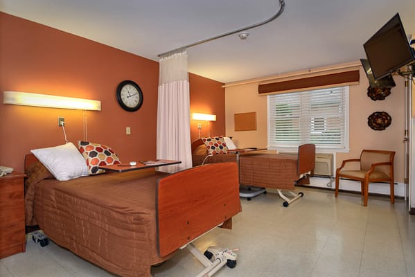 A cozy resident room with two beds and a chair