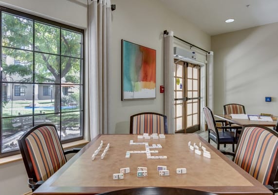 Residents playing dominoes in a sunny common area