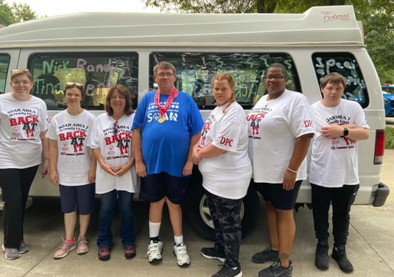 Group of staff and residents in front of facility van