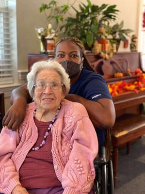 A caregiver with a resident smiling in a common area