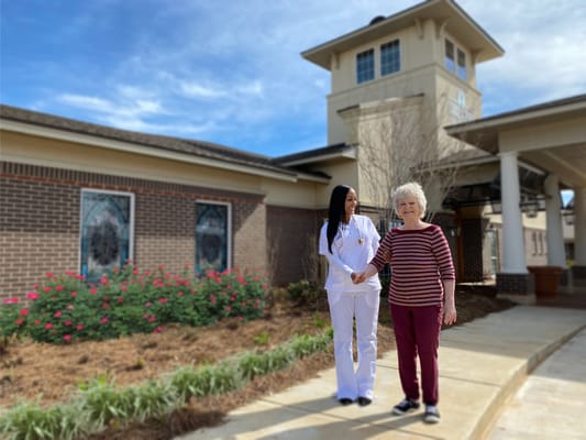 A staff member and resident walking outside the facility