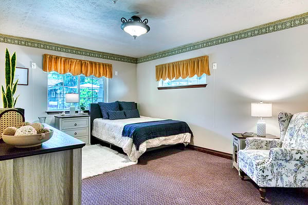 Bright and inviting resident room with a bed and armchair