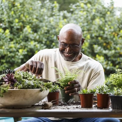 A joyful resident gardening in a sunny outdoor space