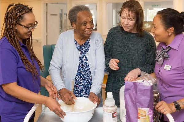 Residents and staff cooking together in a kitchen