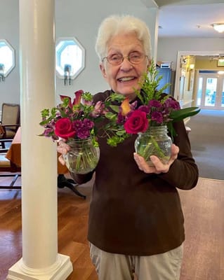 Resident holding two flower arrangements in the common area