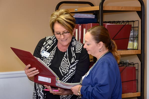 Two staff members discussing documents in an office setting