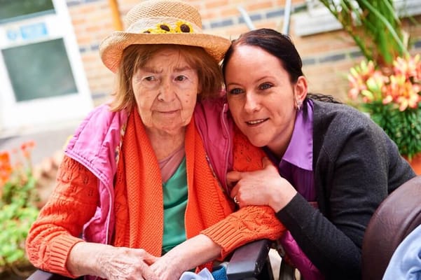 A resident and staff member in an outdoor garden area