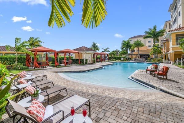 Resort-style outdoor pool with lounge chairs and cabanas