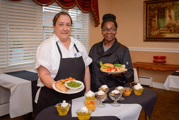 Two staff members presenting meals in a dining area