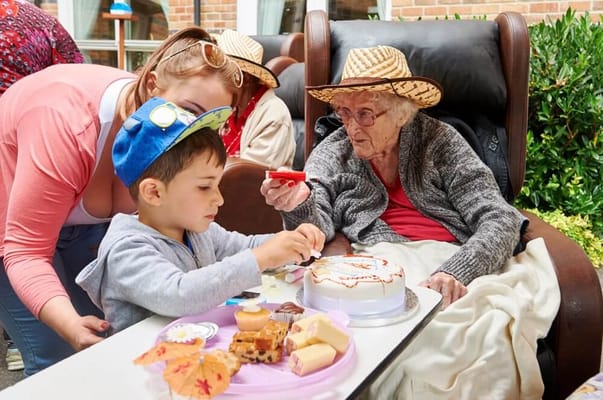 Child and elderly resident enjoying cake together