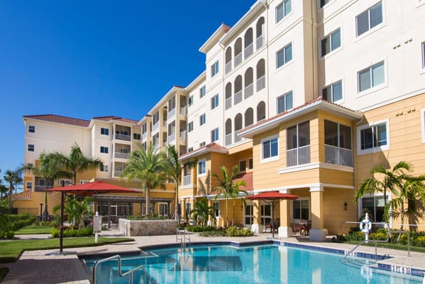 Exterior view of the facility with a pool and palm trees
