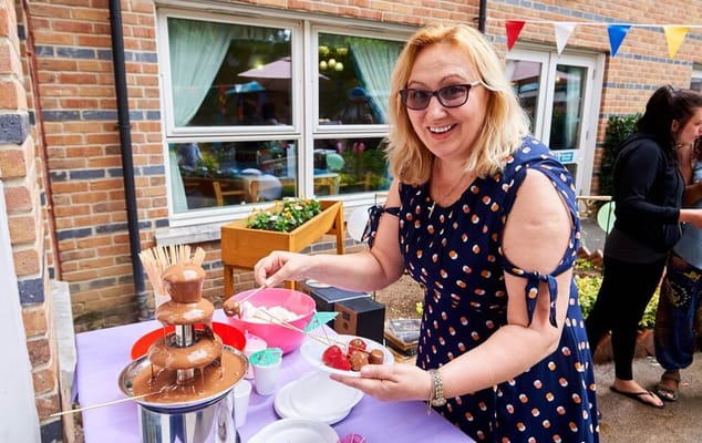 A staff member serving food at a festive outdoor event