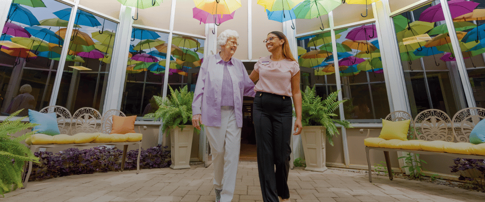 Staff walking with a resident in a colorful atrium