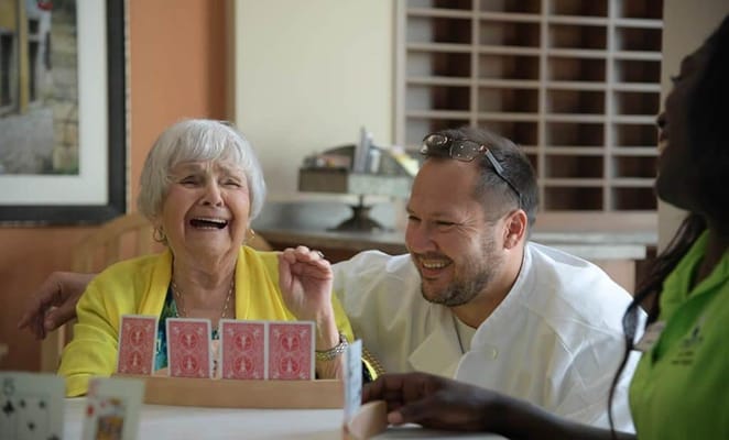 Residents and staff enjoying a card game in a common area