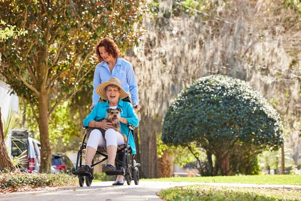 A caregiver pushing a resident in a wheelchair outdoors