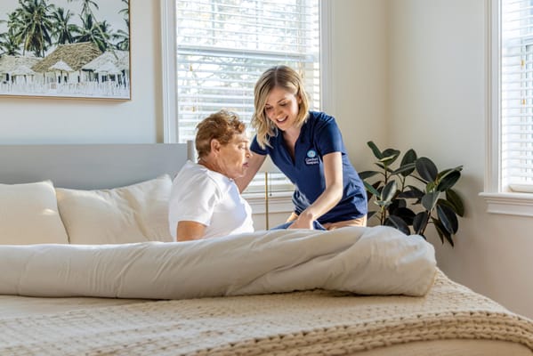 Caregiver assisting a resident in a bright bedroom
