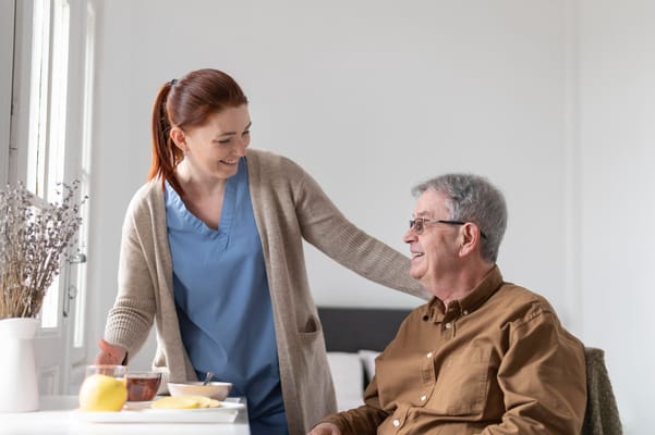 A caregiver interacts with a senior resident in a bright room