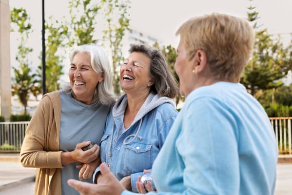 Three senior women laughing together outdoors