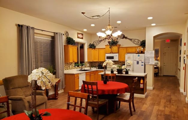 A warm kitchen and dining area with wooden cabinets, a round table, and comfortable seating.