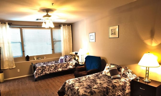 Cozy bedroom with two twin beds, a chair, and a window with curtains.