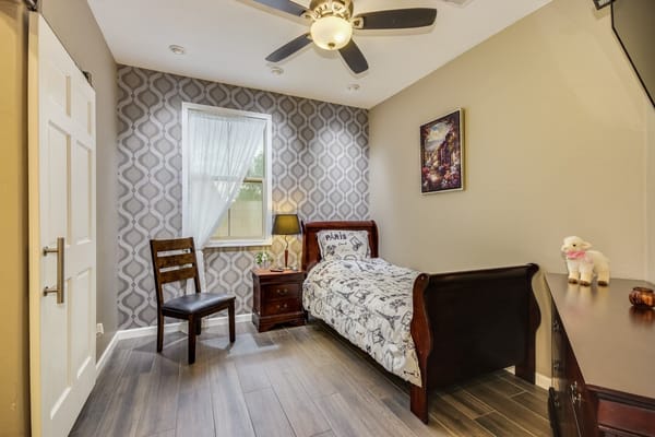 A cozy bedroom featuring a bed, chair, and decorative elements.