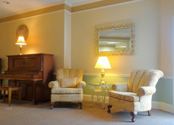Lounge area with two upholstered chairs, piano, and lamp