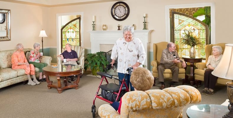 Seniors interacting in a comfortable common area with seating and natural light.
