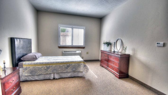 A private resident room with a bed and dresser