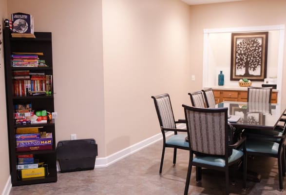 Dining area with a wooden table and chairs, bookshelf with games
